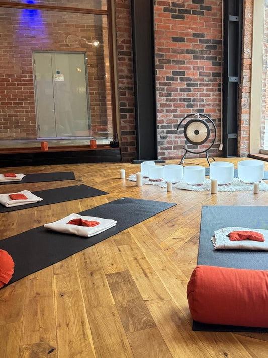 Yoga studio with mats and pillows on a wooden floor against a brick wall.